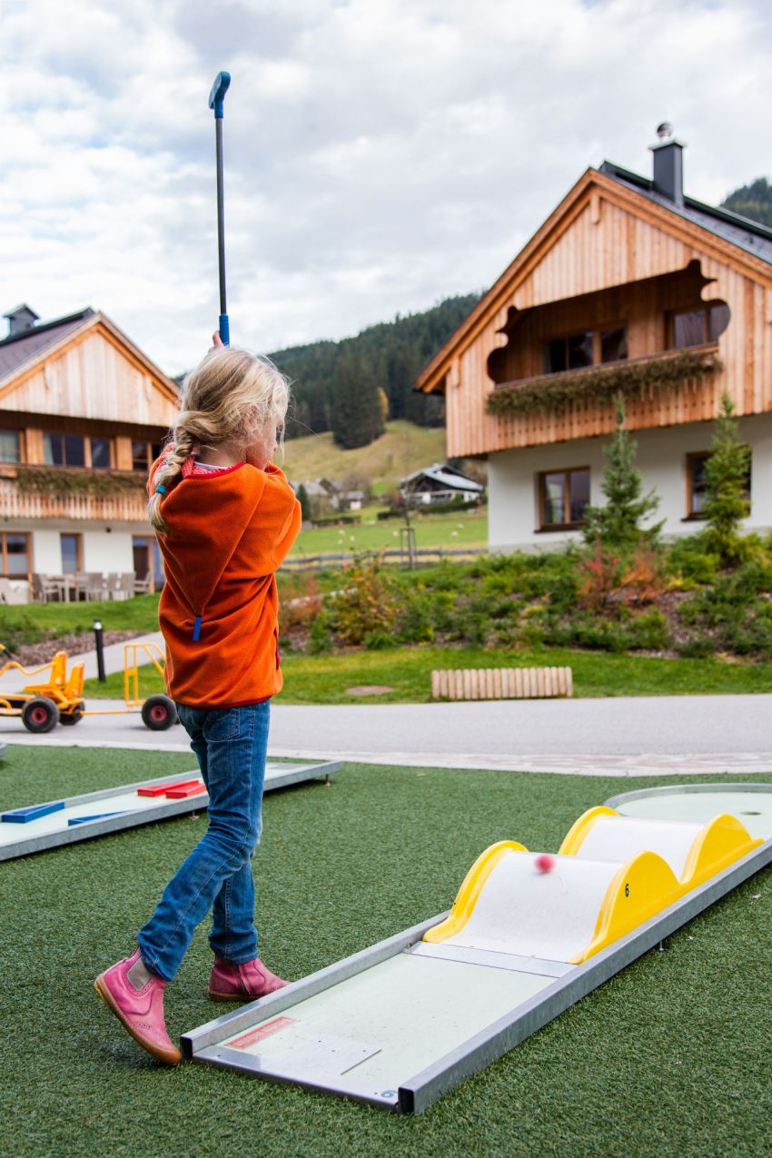 Ein junges Mädchen spielt Minigolf und schwingt dabei mit ihrem Schläger durch die Luft.  Ein junges Mädchen spielt Minigolf und schwingt dabei mit ihrem Schläger durch die Luft.