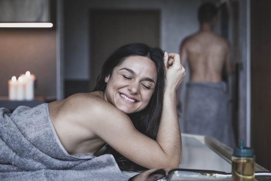 Close-up of a happy woman covered with a towel lying on a massage table.