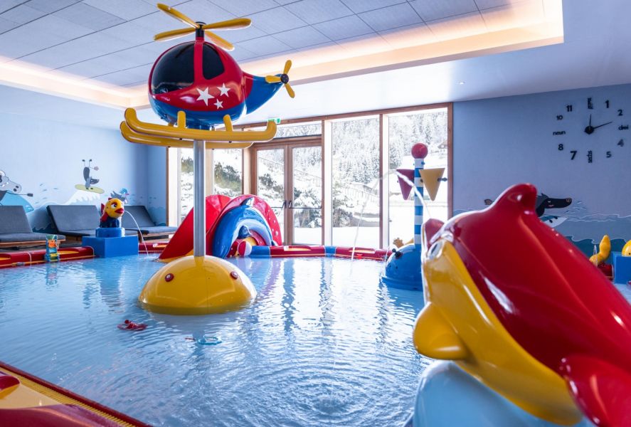 Colorfully designed indoor children's pool with slides, water fountains, and a view out into the snow. Colorfully designed indoor children's pool with slides, water fountains, and a view out into the snow.