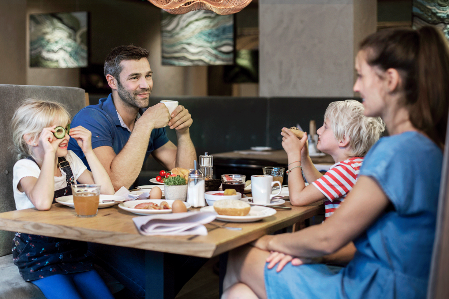 A family of four sitting smiling at a set breakfast table. A family of four sitting smiling at a set breakfast table.