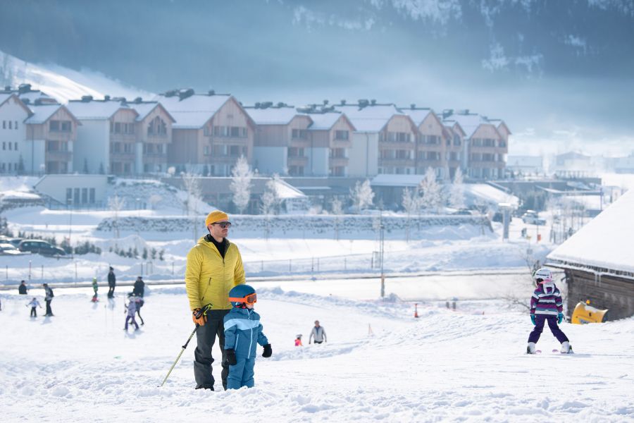 Ein Mann steht mit einem Kind im Schnee an einem kleinen Skiberg für Kinder. Ein Mann steht mit einem Kind im Schnee an einem kleinen Skiberg für Kinder.