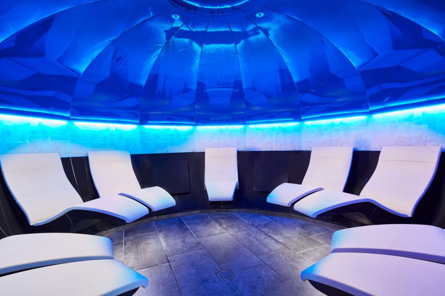 Wellness area with several white loungers standing in a circle and dark blue lighting. Wellness area with several white loungers standing in a circle and dark blue lighting.